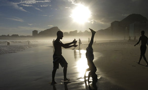 A boy does a headstand at sunset on Copacabana Beach in Rio de Janeiro